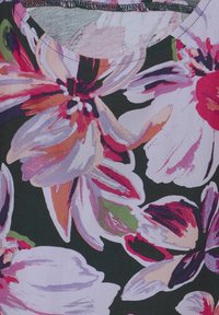 Blommig blus med stora rosa, lila och röda blommor på en svart bakgrund. Tyget har en jämn textur; rund halsringning med kontrasterande sömnad.