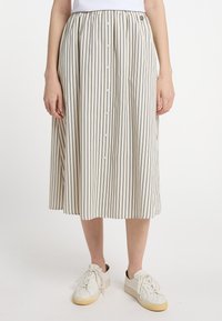 Stribet midi-nederdel i creme og marineblå, med en samlet talje, frontknaplukning og letvægtsstof. Bæres med hvide sneakers.