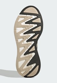 Die Schuhsohle verfügt über ein Zickzackmuster aus schwarzem und beigefarbenem Gummi mit strukturierten Oberflächen und Ausschnitten für Flexibilität und Grip.