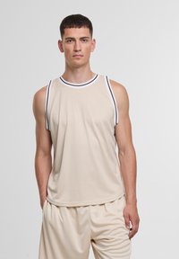 Beige ilma varrukatega sportlik topp musta ja valge triibulise kaelusega. Sile kangas, mugav lõige, koos sobivate beežide lühikeste pükstega.