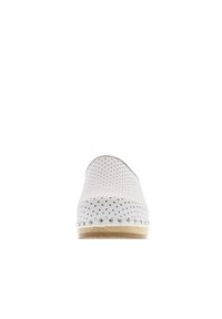 White shoe with black polka dots, rounded design, smooth leather-like material, tan sole, and decorative silver studs along the edge.