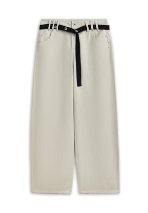 Pantalon large couleur beige clair avec poches avant et une fine ceinture noire passant dans les passants de ceinture, pendante à l'avant.