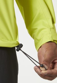 Chaqueta ligera de color amarillo brillante con ajuste de cordón en el dobladillo, con toggles elásticos y una textura de tela suave.