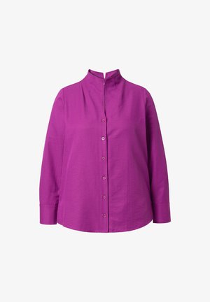 Lilla skjorte med knaplukning og mandarin krave, lange ærmer og glat tekstur. Har seks knapper på forsiden.