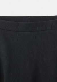 Kratak prikaz crne rebraste tkanine koja prikazuje presavijen pojas, ističući teksturu i detalje šivanja.