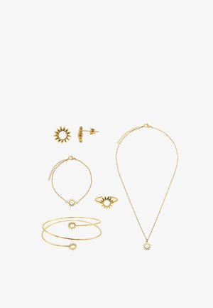 Ensemble de bijoux en or avec des motifs en forme de soleil, comprenant des boucles d'oreilles, des bracelets, une bague et un collier sur fond blanc.