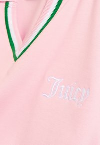 Tecido cor-de-rosa com gola em V riscada verde e branca e texto bordado a branco a dizer "Juicy".