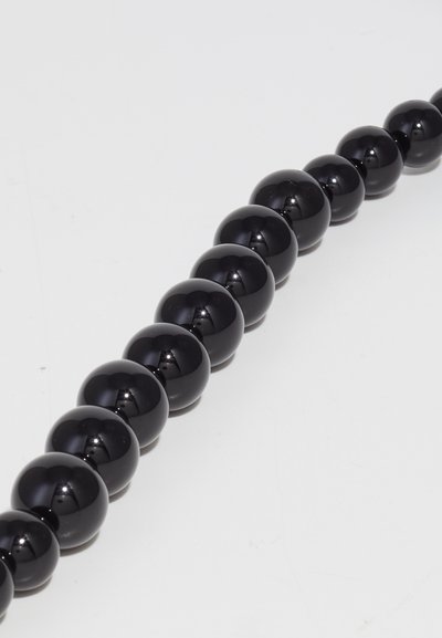 Μαύρες σφαιρικές χάντρες με λεία, γυαλιστερή επιφάνεια, ευθυγραμμισμένες σε μία σειρά, επιδεικνύοντας ομοιόμορφο μέγεθος και σχήμα σε λευκό φόντο.