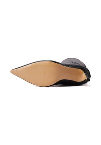 Tacco a stiletto nero con punta affusolata, caratterizzato da una superficie liscia e una suola beige a contrasto con delicate rigature.