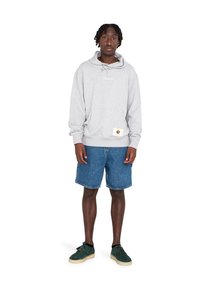 Gray hoodie with a kangaroo pocket, featuring a white logo. Paired with blue denim shorts and green suede shoes with cream soles.