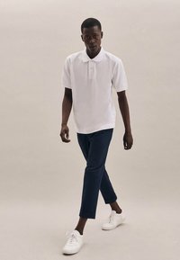 Biela polokošeľa s krátkym rukávom, námornícke úzke nohavice a biele tenisky, s hladkou textúrou látky a voľným strihom.