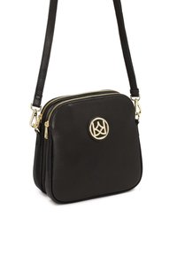Borsa a tracolla nera in pelle con doppie zip, un accento rotondo con logo dorato, tracolla regolabile, texture liscia e forma rettangolare.