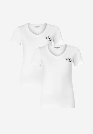 Λευκό μπλουζάκι v-neck με μικρό μαύρο λογότυπο, μπλε skinny jeans και μαύρες πλατφόρμες-γκλόκ. Απαλή υφή, κλασική εφαρμογή και μινιμαλιστικός σχεδιασμός.