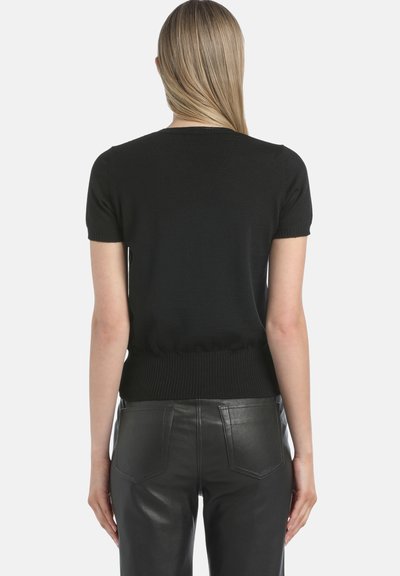 Juodas trumpomis rankovėmis megztinis, prigludusios formos ir su ripsu apdaila, derinamas su juodomis odinėmis kelnėmis, turinčioms galines kišenes.