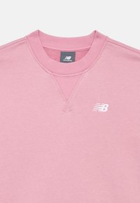 Sweatshirt rosa de corte crewneck com gola canelada, pequeno logótipo branco da New Balance bordado no peito e etiqueta na parte interna do decote.