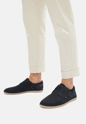 Czarne buty z tkaniny o niskim profilu, z wiązaniem na sznurówki, wyposażone w beżową podeszwę, kontrastowe przeszycia oraz subtelne logo.