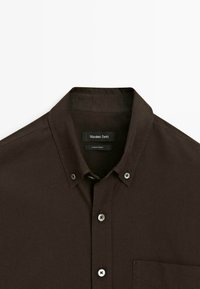 Camicia button-up di colore marrone scuro con taschino, colletto button-down e etichetta interna "Massimo Dutti" realizzata in Turchia.
