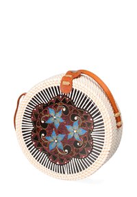 Borsa rotonda intrecciata con esterno in vimini bianco, interno a motivo nero con fiori blu e tracolla in pelle color cammello.