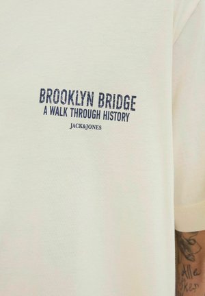 Wit T-shirt van katoen, met marineblauwe tekst die "BROOKLYN BRIDGE A WALK THROUGH HISTORY JACK&JONES" leest. Korte mouwen, eenvoudig ontwerp.