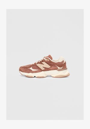 Rjavi nubuk tenisky s kremnimi detajli, ki vključujejo teksturiran dizajn, zavezovanje z vezalkami in oblazinjen podplat. Klasičen logotip New Balance je viden.