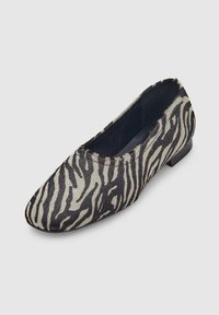 Platte schoen met een zwart-wit zebra print en een lage hak, met een ronde neus en een zachte textuur.