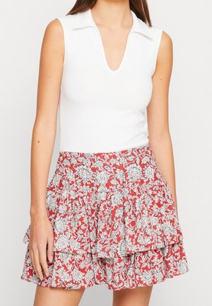 Weißes ärmelloses Oberteil mit Kragen, kombiniert mit einem roten, gerafften Rock mit weißem Blumenmuster und elastischem Bund.