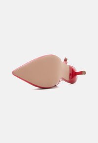 Ροζ παπούτσι με τακούνι υψηλό από δερμάτινο βινύλιο με μυτερή μύτη, λεπτό στιλέτο τακούνι και λεία σόλα, με ελάχιστο μεταλλικό εξάρτημα και υφή στην επιφάνεια του πέλματος.