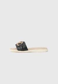Black slide sandal with a smooth leather strap featuring a gold-tone circular hardware detail. Soft beige footbed and textured sole.