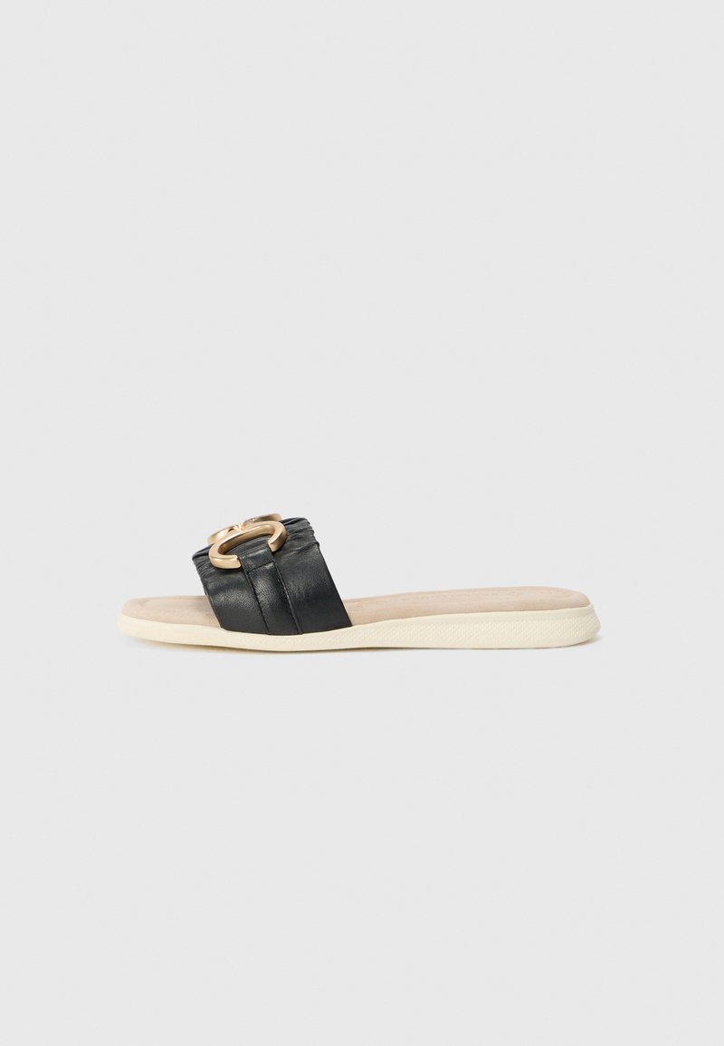 Black slide sandal with a smooth leather strap featuring a gold-tone circular hardware detail. Soft beige footbed and textured sole.