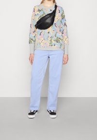 Mångfärgad sweatshirt med blommönster och grå manchetter, ljusblå raka jeans, svart midjeväska och svartvita sneakers.