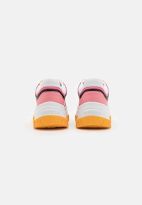 Baskets avec une tige en mesh blanche, des accents roses et noirs, et une semelle en caoutchouc orange texturée. Présentent un logo "GUESS" sur le talon.