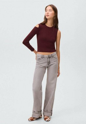Burgundy kortärmad tröja med en axelavskärning, i kombination med ljusgrå vida jeans och bruna och vita mönstrade skor.