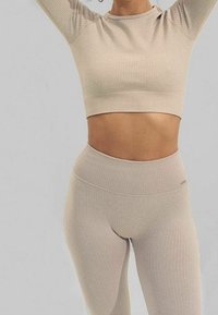 Conjunto de top corto de canalé beige y leggings de talle alto. Presenta una textura suave y tela elástica, diseñado para comodidad y flexibilidad.