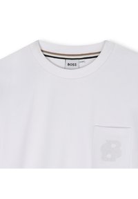 Fehér, pamut póló, amelyen zseb található, rajta dombornyomott "B" betű hímzéssel, valamint kontrasztos csíkos nyakkivágással. Egyszerű és letisztult dizájn.