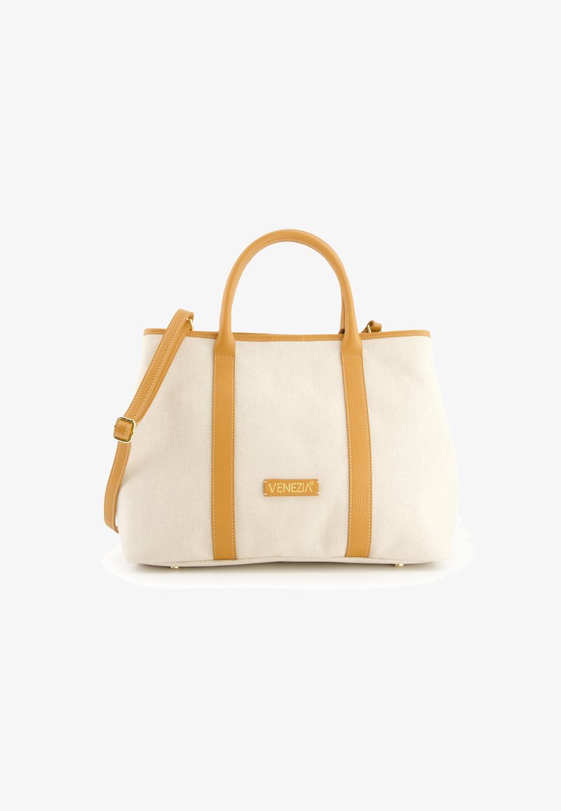 Sac fourre-tout en toile beige avec des anses et des accents en cuir jaune, comportant un logo en patch à l'avant et une bandoulière amovible.