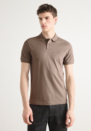 Polo en coton marron avec col et patte de boutonnage à trois boutons, doté d'une petite étiquette logo sur la poitrine et de manches courtes.
