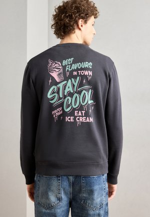 Sötét szürke pulóver, amelynek hátulján színes jégkrém minták találhatók, menta zöld és rózsaszín felirattal. Bordás mandzsetták és hem.