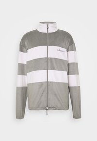 Sammet zip-up jacka med hög krage. Grå och vita horisontella ränder. Har framzipstängning och justerbar nederkant med dragsko.