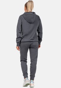 Completo con felpa e pantaloni grigi realizzato in materiale morbido; presenta un cappuccio con coulisse, polsini a costine e un dettaglio della tasca posteriore.