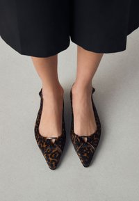 Ballerines à bout pointu imprimé léopard, dotées d'une texture douce et d'une petite découpe avec une garniture en argent. Semelle plate ; design élégant.