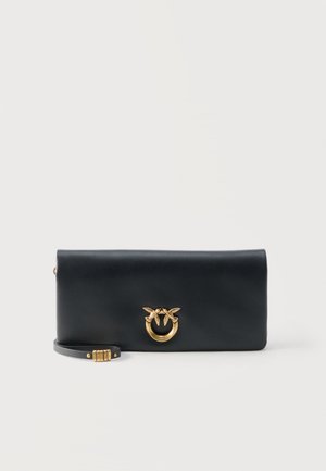 Bolso de mano de piel negra con cierre dorado que presenta dos pájaros en un anillo circular y una correa de muñeca desmontable con una cerradura combinada dorada.