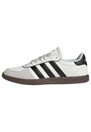 White leather sneakers with black stripes, rounded toe, and textured suede accents on the side. Brown rubber sole with logo detail.