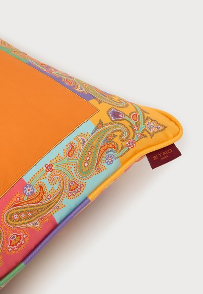 Coussin rectangulaire avec un centre orange et une bordure paisley colorée en jaune, bleu, violet et rouge, avec une petite étiquette sombre indiquant "ETRO HOME."
