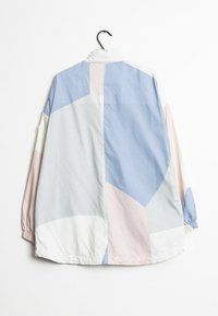 Chaqueta ligera con un diseño de bloques de color en tonos pastel de azul, rosa y blanco. Incluye un cuello alto y puños elásticos.