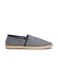 Modra denim slip-on obutev z zaobljenim prstom, jutenim podplatom in vzorčastim notranjim podloženjem. Ima majhen logotip na strani.