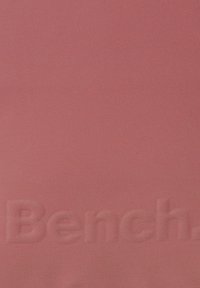 Tissu rose avec une surface texturée et un logo "Bench" en relief. Couleur uniforme, texture lisse, sans motifs ni accents visibles.