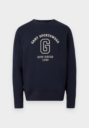 Sweatshirt col ras du cou bleu marine avec texte blanc "GANT SPORTSWEAR", grand logo "G" et "NEW HAVEN 1949" centré sur le devant.