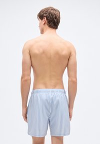 Μπλε και λευκά ριγέ μαγιό βερμούδα με ελαστική μέση, κατασκευασμένα από ελαφρύ ύφασμα, με άνετη εφαρμογή και χωρίς τσέπες.