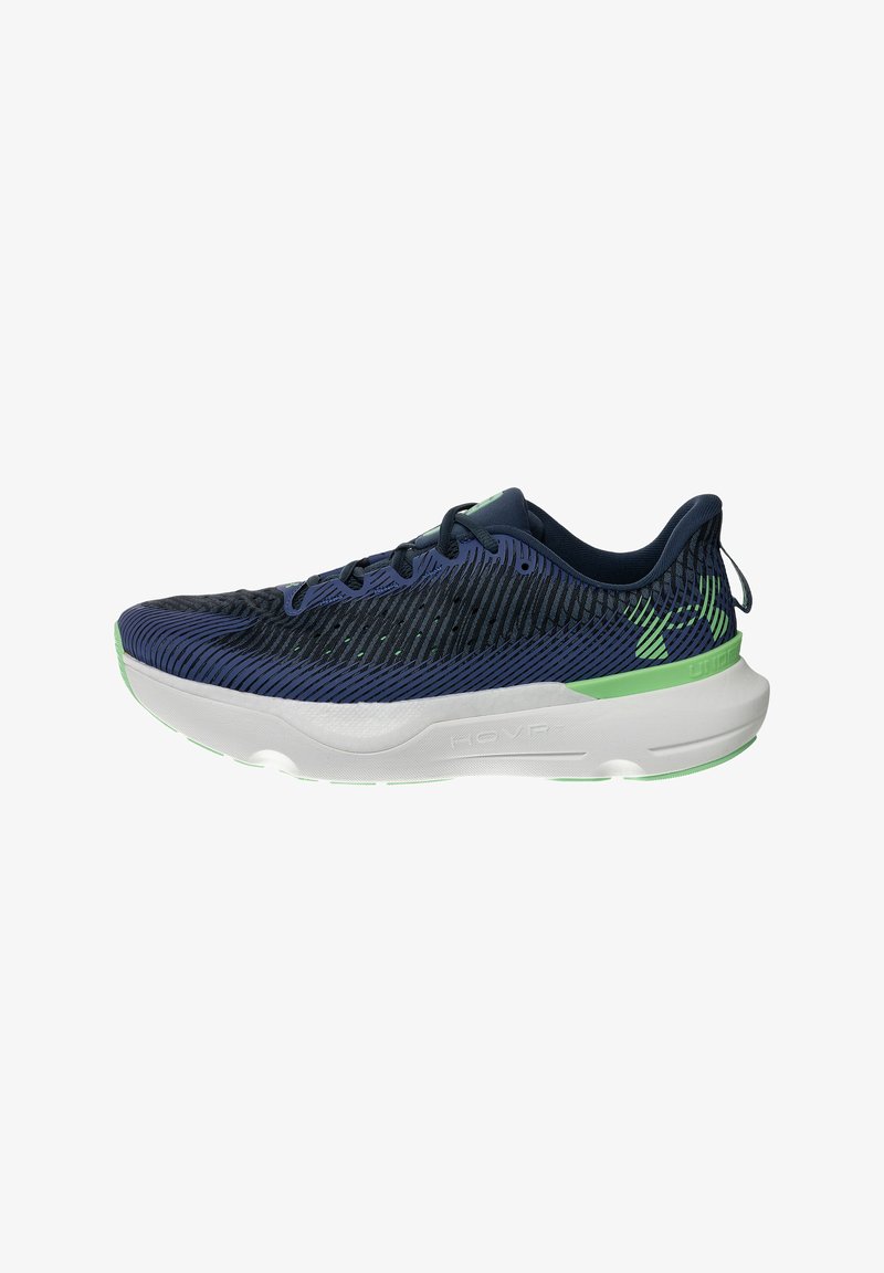 Heren hardloopschoenen in marineblauw en zwart met lichtgroene accenten en een dikke witte zool, zijaanzicht, Under Armour HOVR-model.