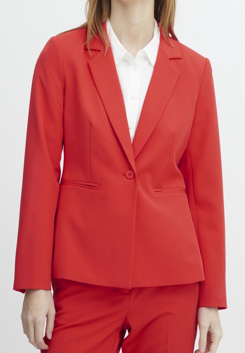 Blazer rouge sur mesure au design élégant, fermeture à un bouton et deux poches avant. Fabriqué en tissu lisse, avec une coupe structurée.